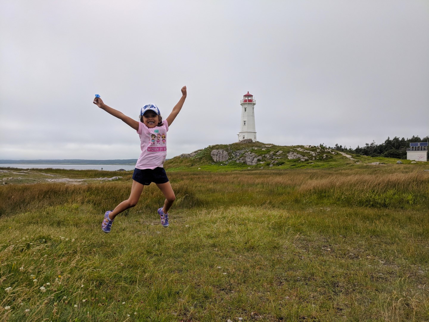 child jumping at louisbourg lighthouse on a Cape Breton Drive