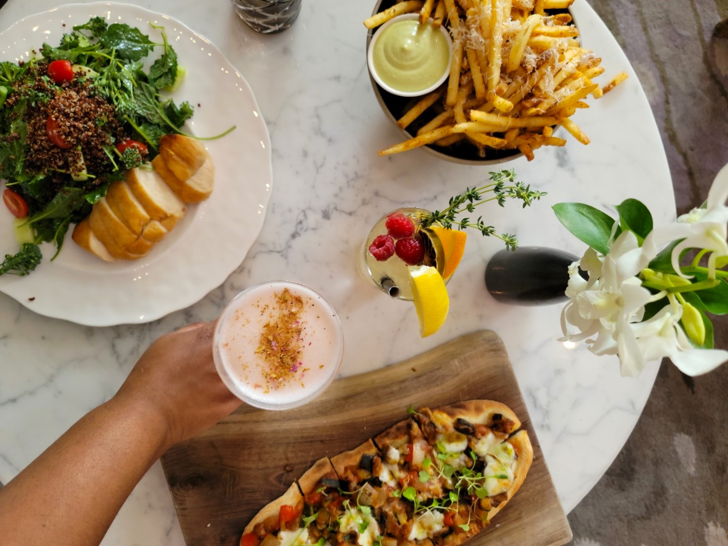 hand grabbing drink with fries and flatbread on table at Toronto Shangrila 