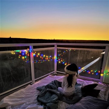 Girl on balcony with lights and sunset in Nova Scotia