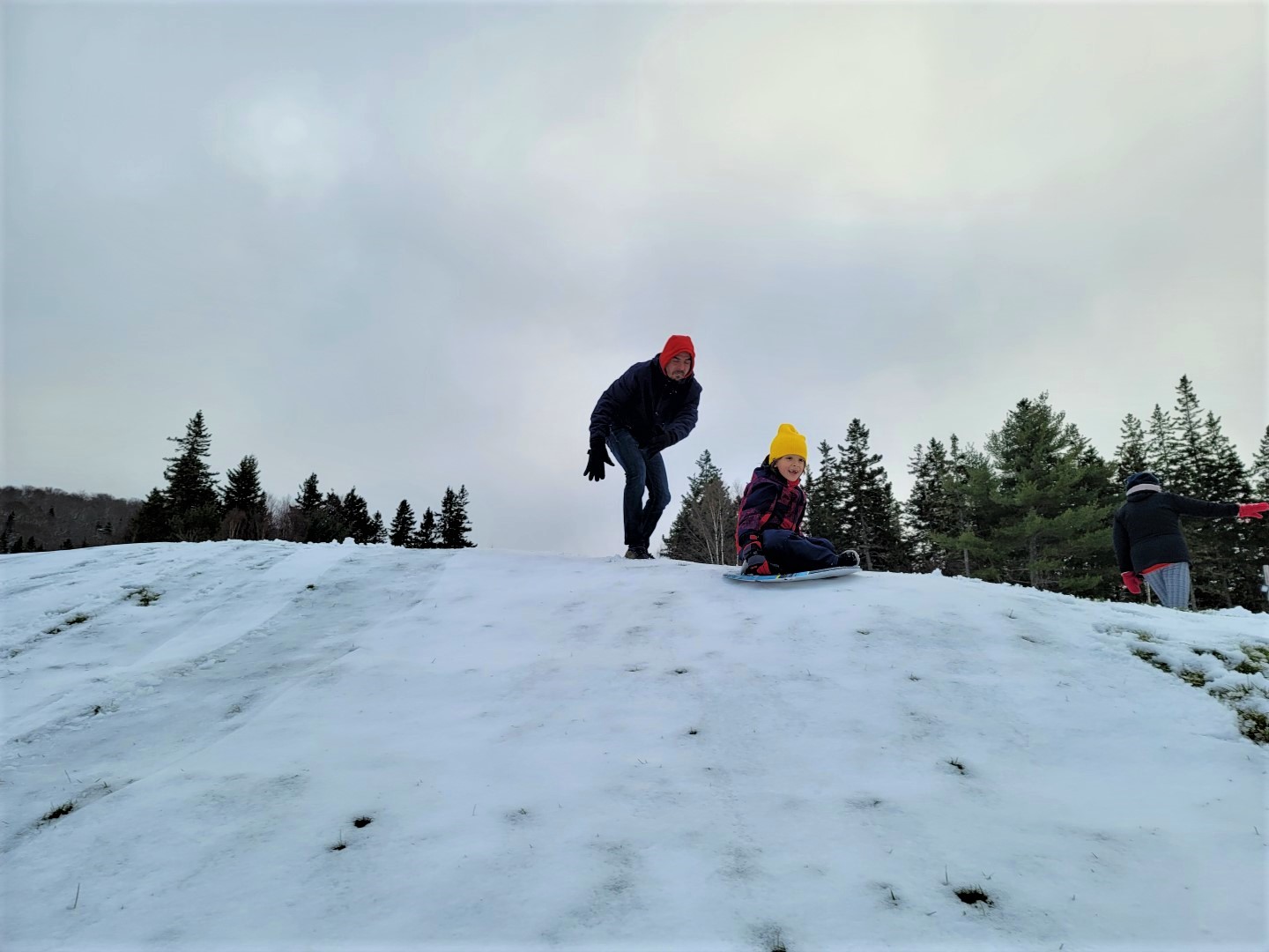 dad pushing son down a snow hill ben eoin
