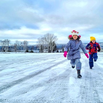 kids dressed in winter coats running in Nova Scotia snow
