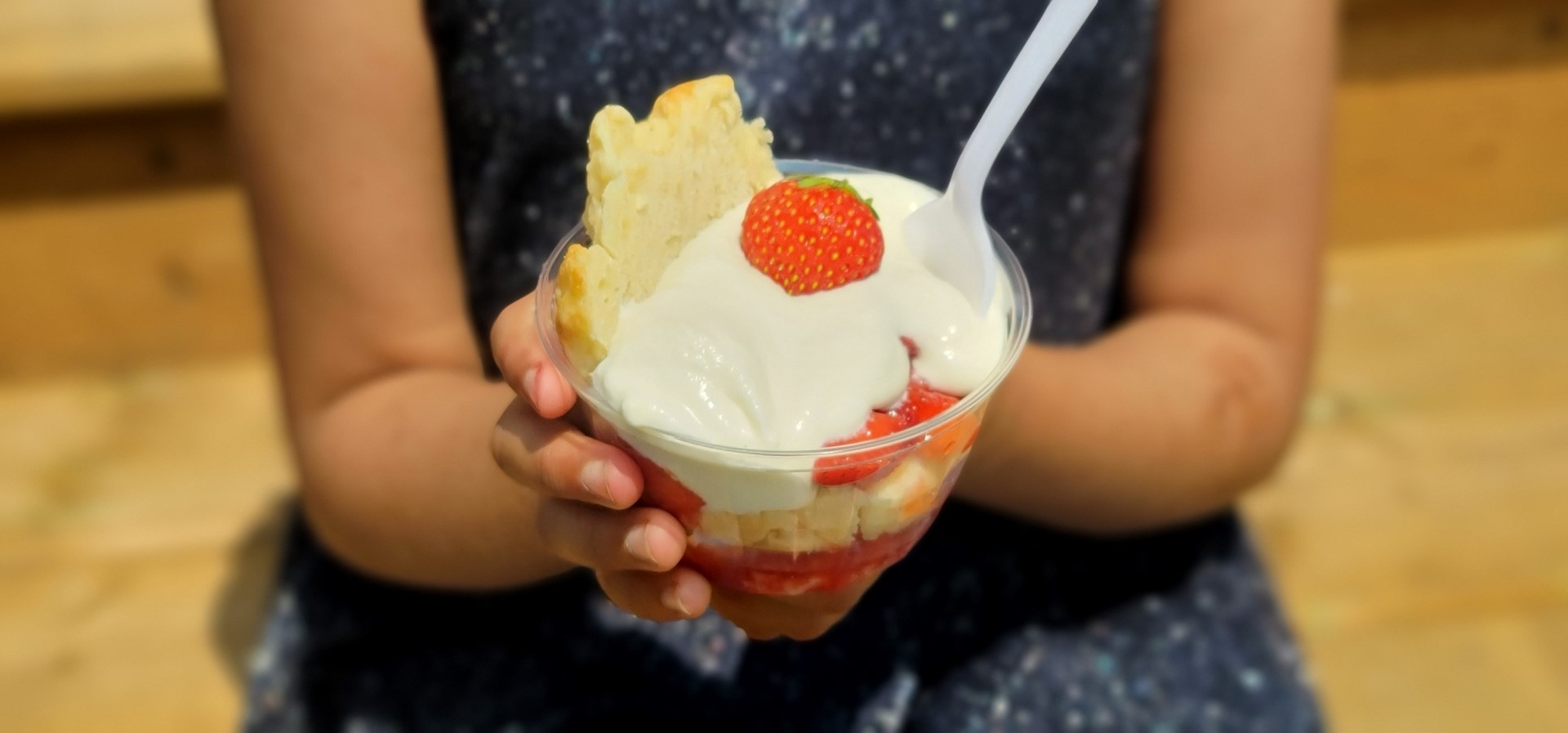 hand holding Strawberry shortcake in cup with white spoon