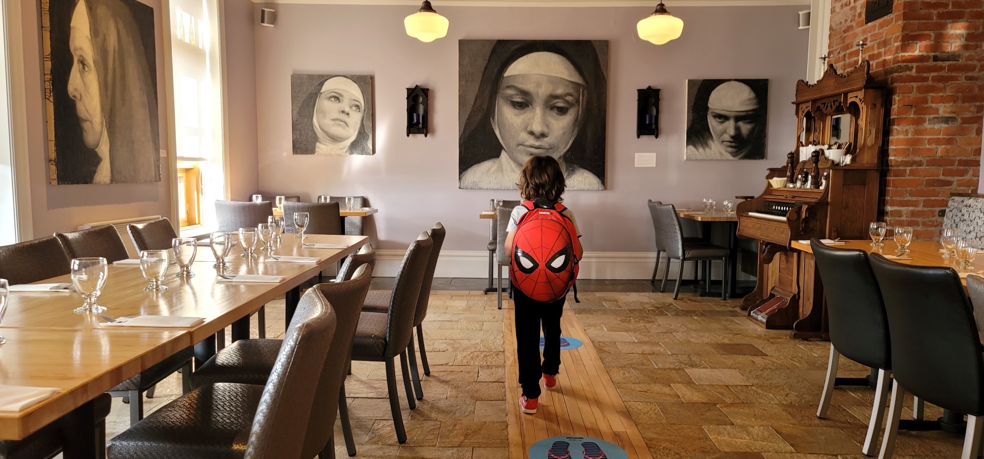 boy with spiderman backpack looking at nun painting