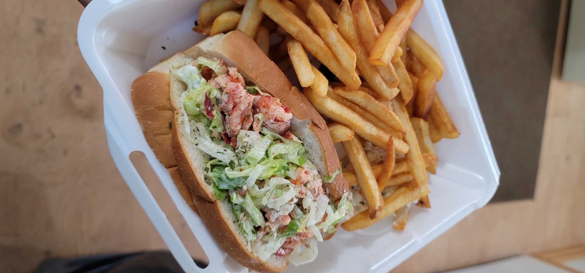 lobster roll and fries in takeout container
