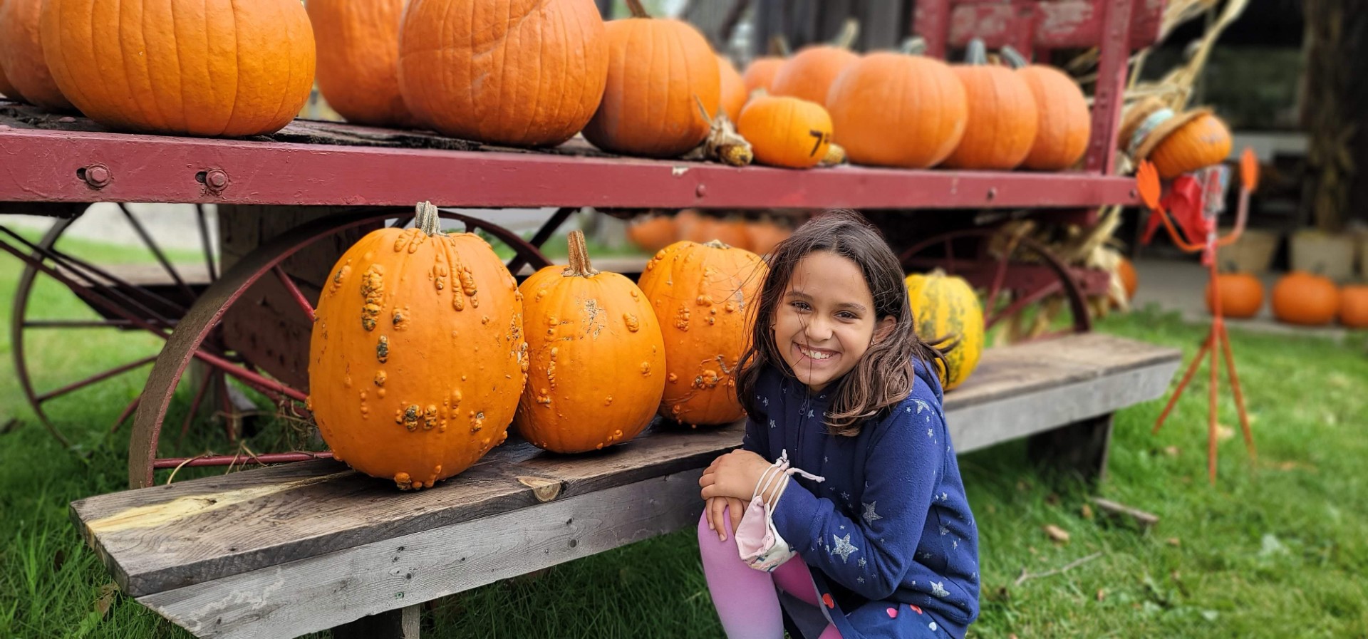 child in front of wart pumpkins