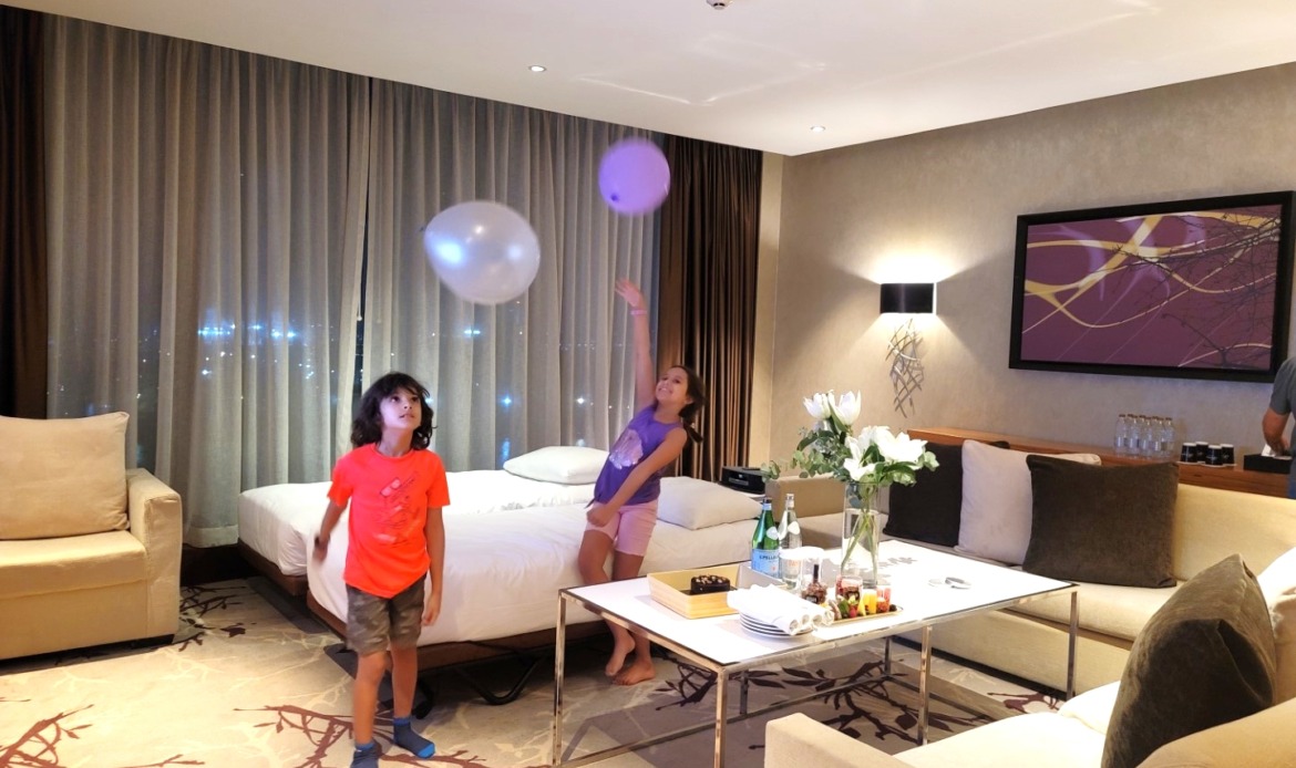 kids throwing balloons in air in hotel room 