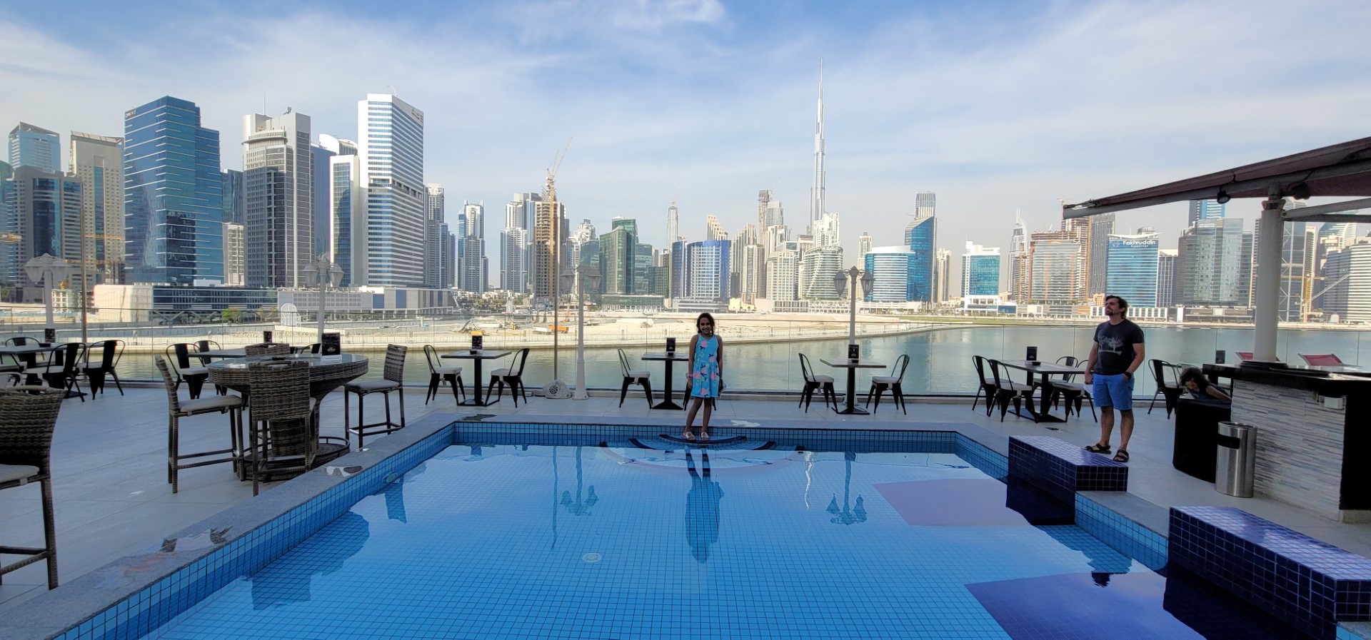 child standing by pool with Dubai skyscrapers in background