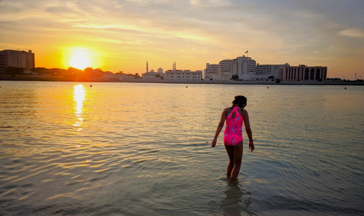 girl walking in water at sunset