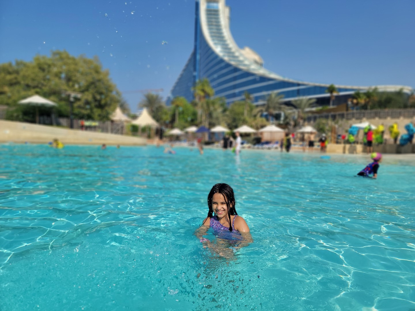 child in water with Jumeirah Beach hotel in background