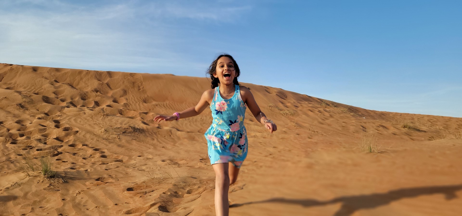 girl in blue dress running in the Arabian desert i