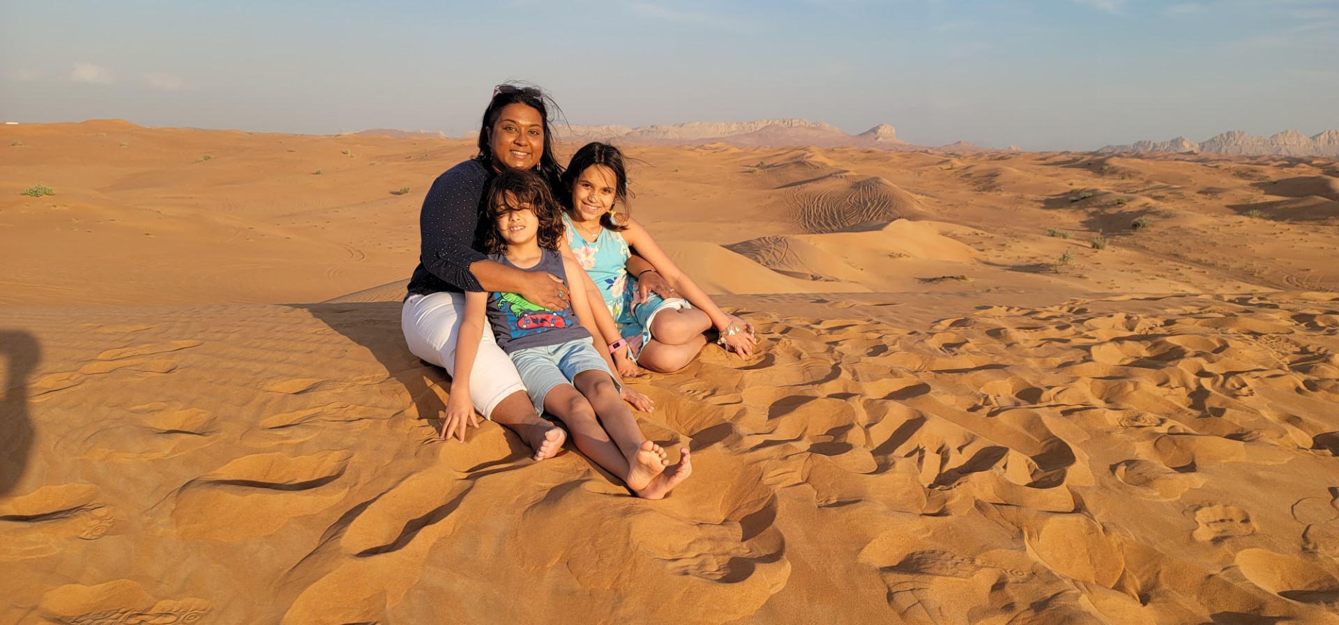 mother and kids sitting on sand dune