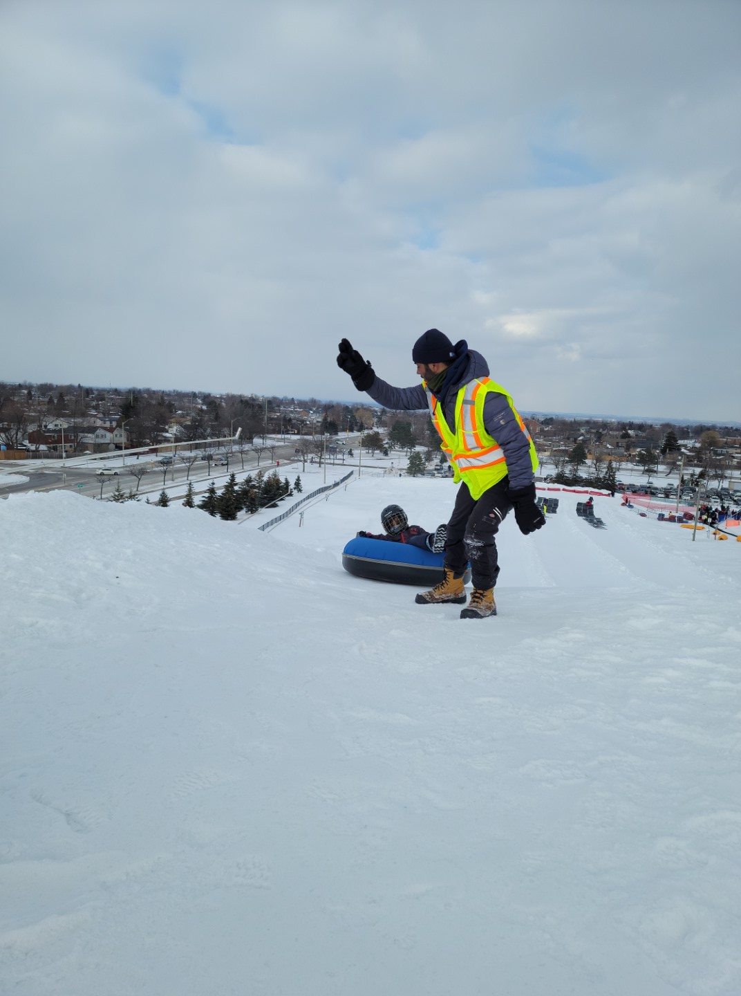 person in vest sending kid down the tubing hill