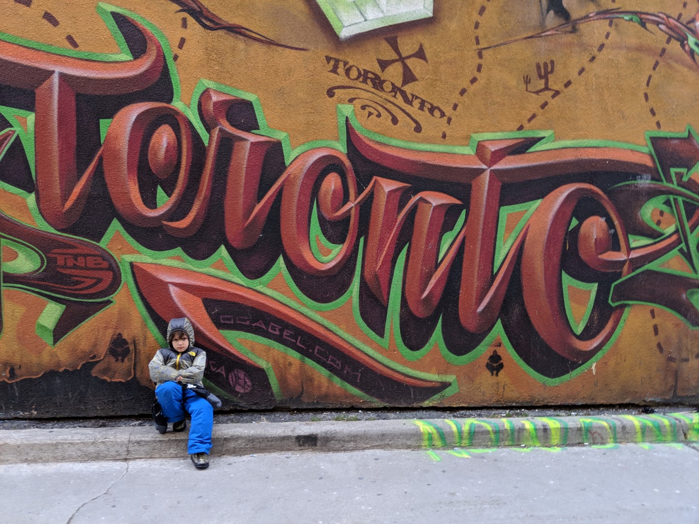 boy in winter gear in front of Toronto graffiti sign