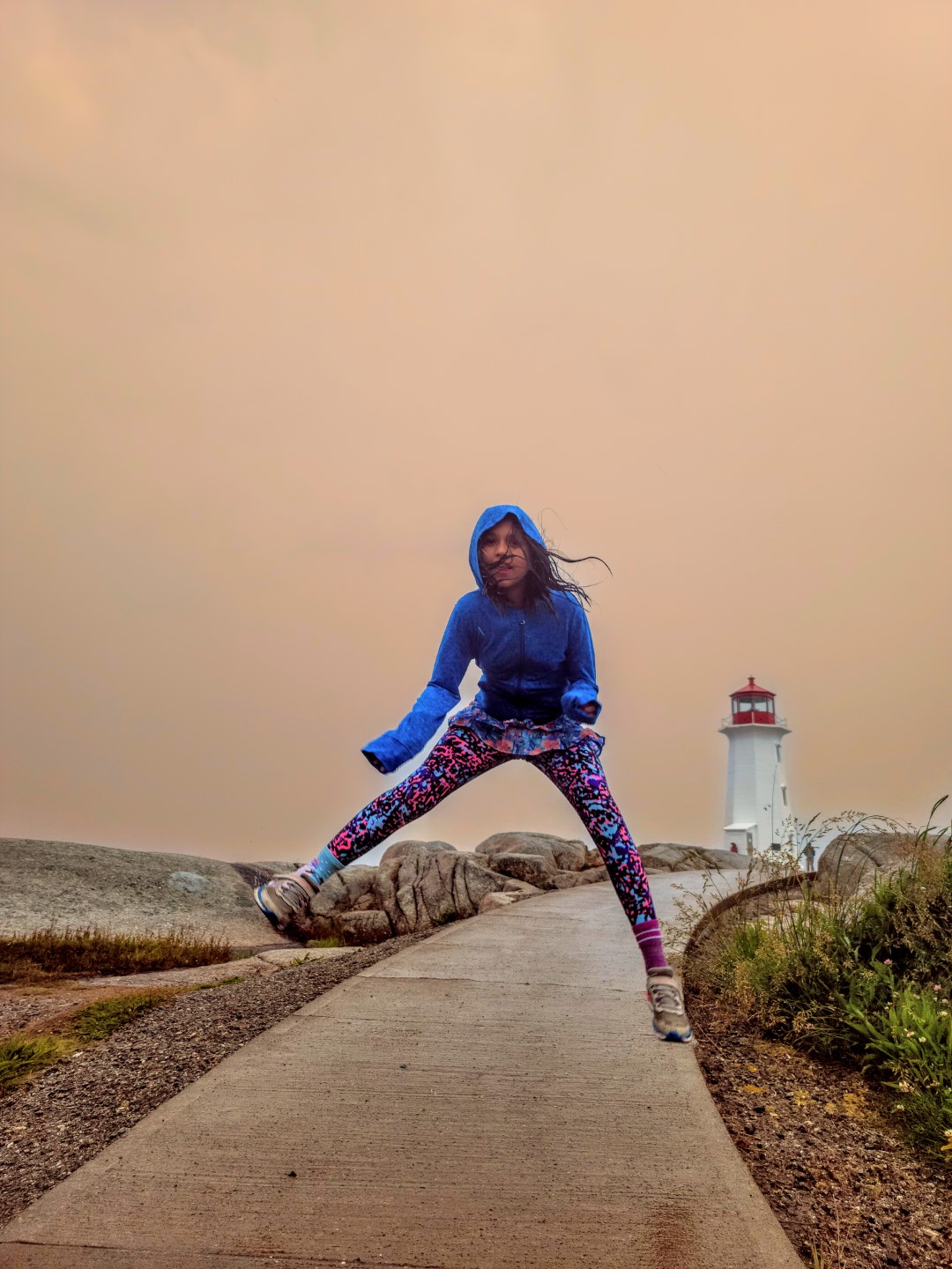girl jumping at Peggy's Cove Lighthouse with kids