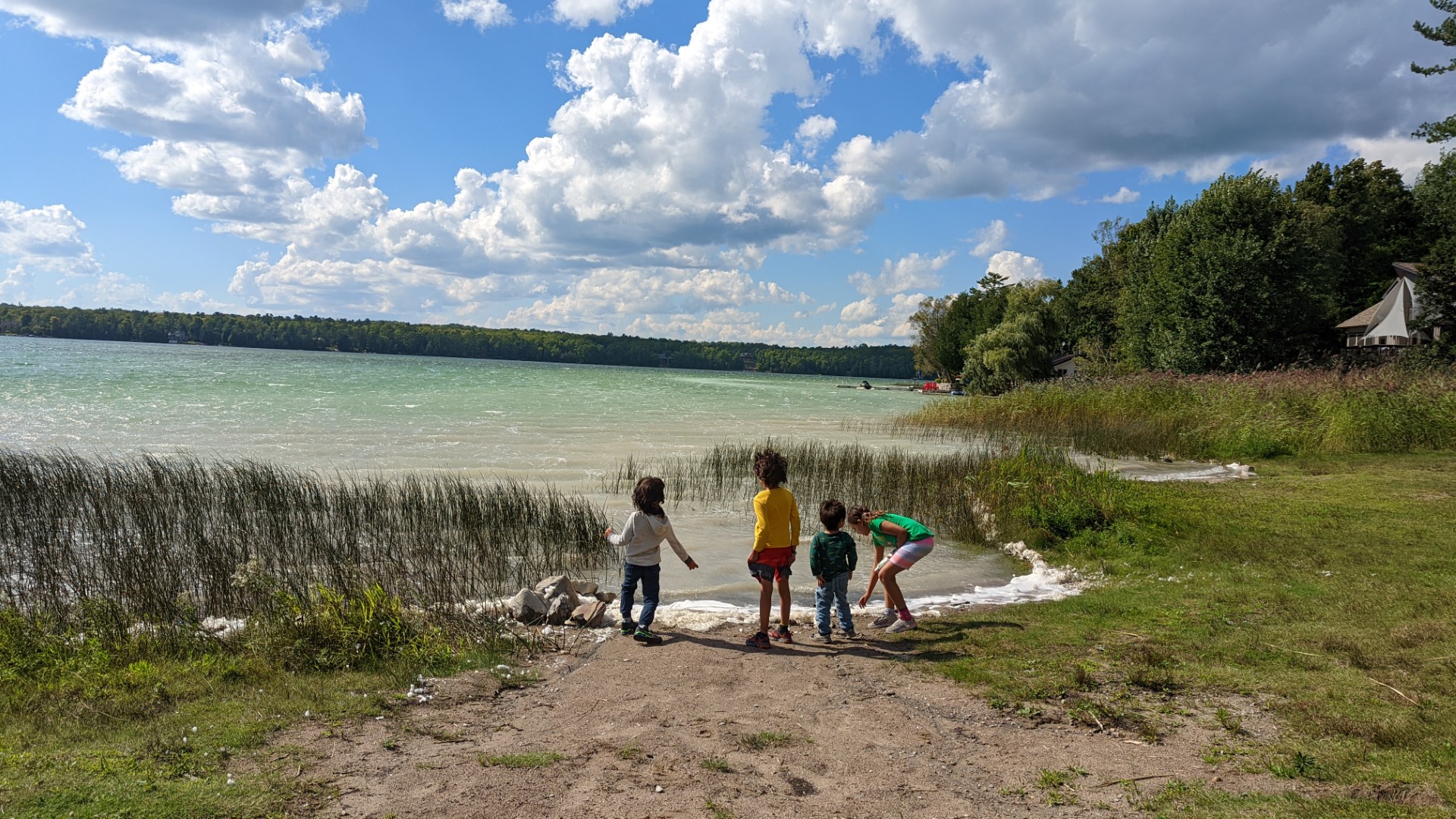 kids playing near sandy Lake with clouds and blue skies