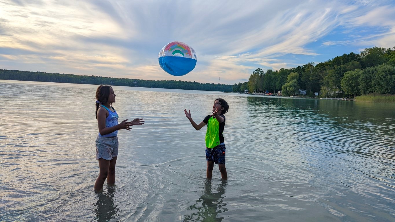 kids playing at Sandy Lake Beach with rainbow ball at sunset
