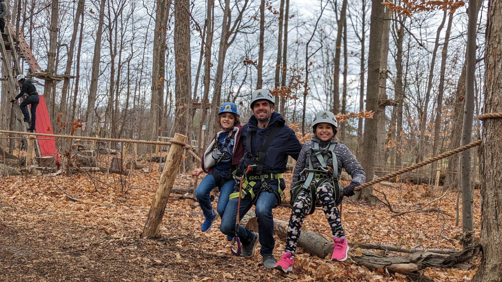 father and children sitting on tree outdoors