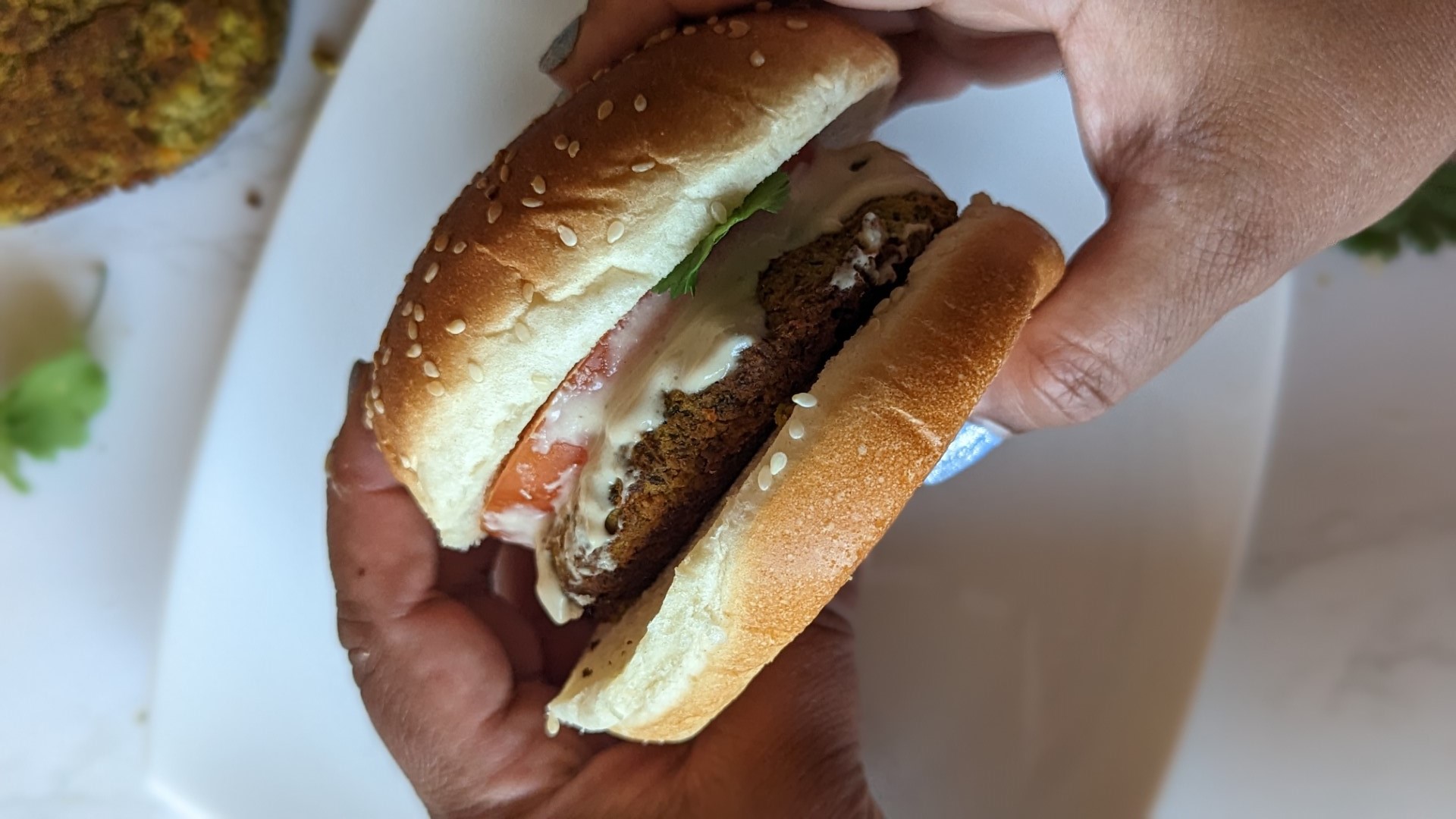 South Asian hands holding falafel burger
