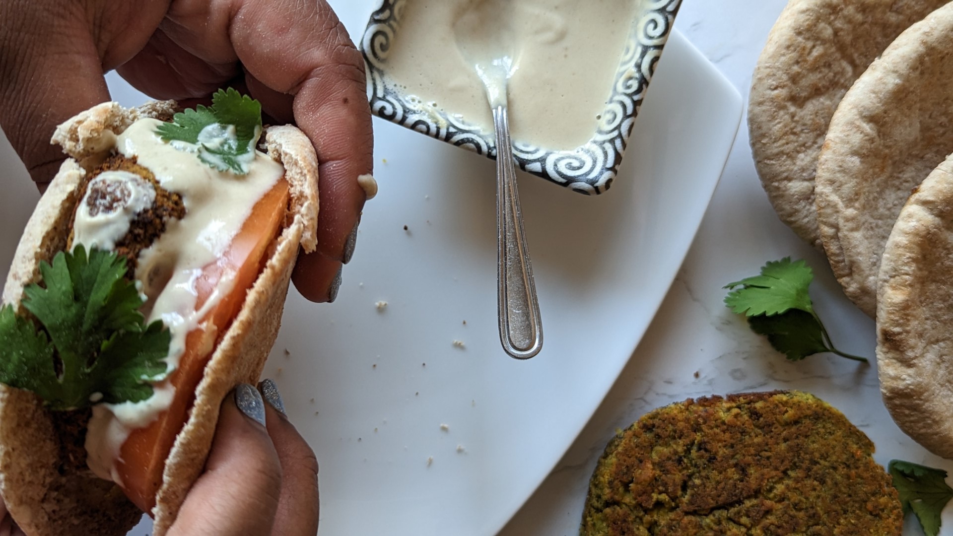hands holding falafel burger in pita