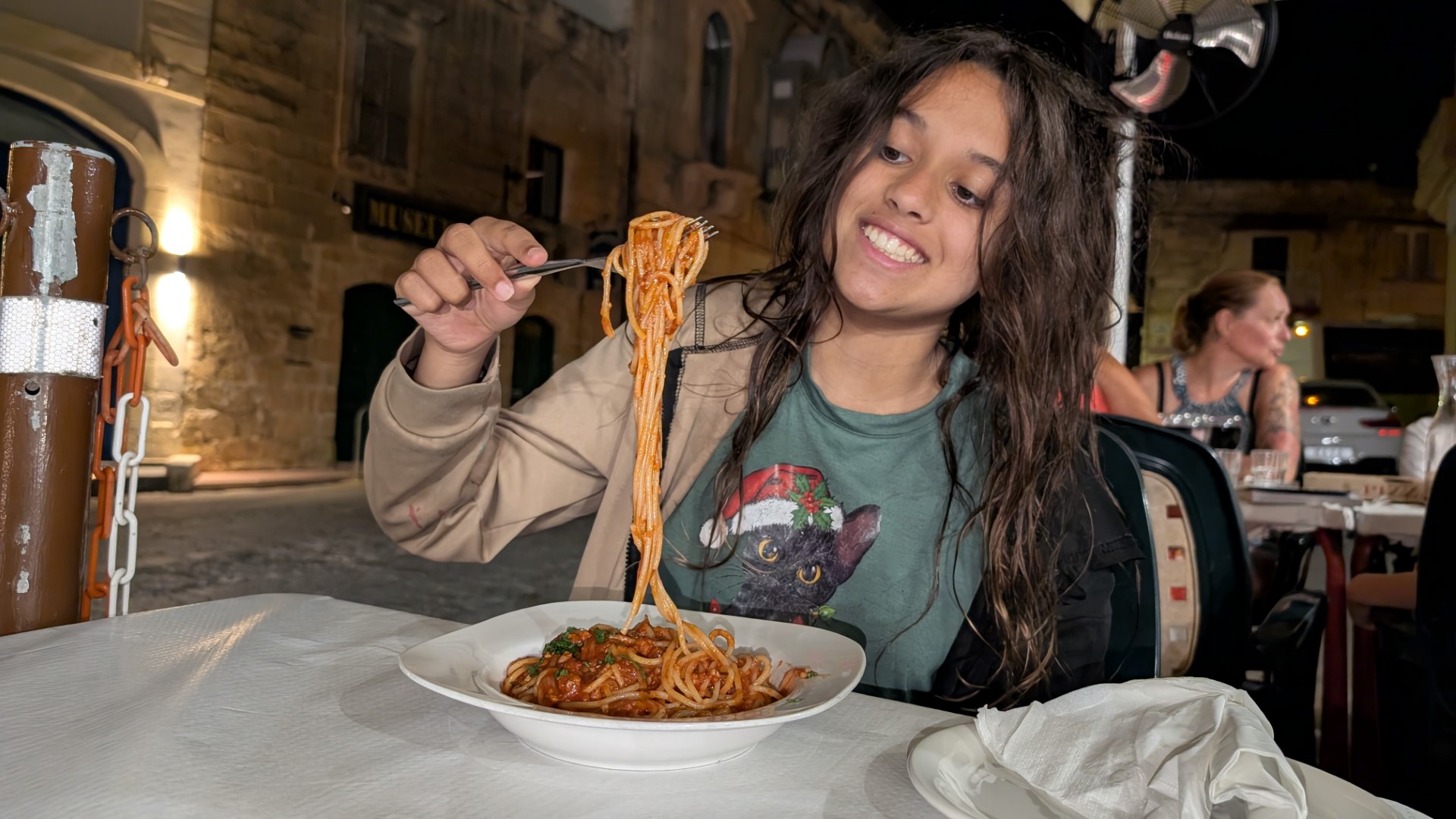 Child smiling and enjoying Maltese food on a patio in Gozo
